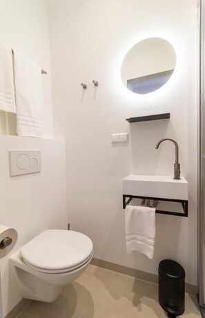 Ein modernes Badezimmer mit Toilette, Waschbecken und Spiegel.