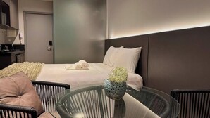 Et moderne hotelværelse med en seng, et glasbord og en stol.