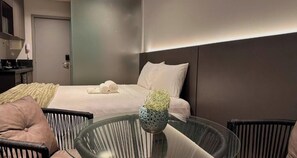 A modern hotel room with a bed, a glass table, and a chair. - Setai Edition - LikeHome  (João Pessoa)