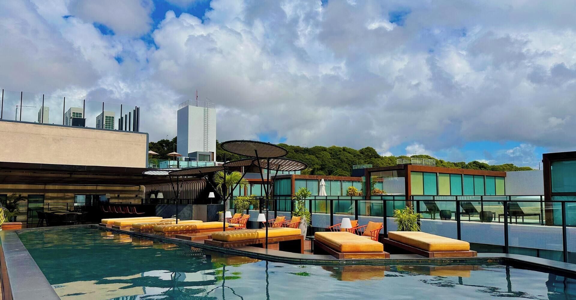 Una piscina al aire libre, sombrillas, sillones reclinables de piscina