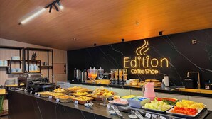 En buffet med et udvalg af madmuligheder, en kaffestation og et skilt med teksten 'Edition Coffee Shop'.