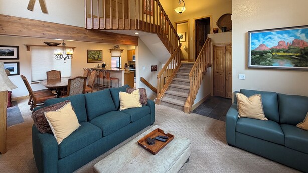 Ein geräumiger Wohnbereich mit zwei Sofas, einem Couchtisch, einem Esstisch und einer Treppe, die in eine obere Ebene führt.