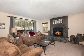 A living room with a stone fireplace, a sofa set, a coffee table, and a lamp. - Pool|2 Hot Tubs|Garage|Fireplace|Elevator|Balcony (Breckenridge)