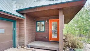Uma casa de madeira com porta vermelha, garagem e varanda.