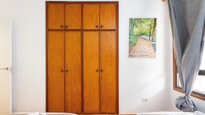 Ein Schlafzimmer mit Holzschrank, Bett und einem Fenster mit Vorhängen.