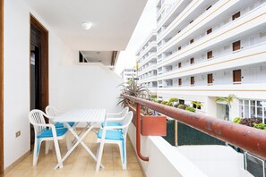 A balcony with a white table and chairs, a view of a multi-story building, and a railing. - Home2Book Cozy Arona Apt with Pool & Terrace (Playa de la Américas)
