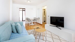 Ein modernes Wohnzimmer mit Sofa, Fernseher und Essbereich.