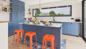 Una cucina moderna con isola centrale, sgabelli da bar e vista attraverso una finestra.