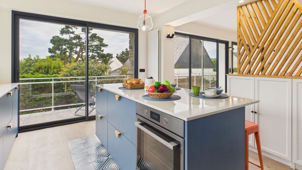 Una cucina moderna con un'isola grande, vista all'esterno e un pannello in legno.