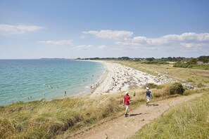 A beach with a clear sky, a sandy shore, and a grassy path leading to the beach. - 600 m beach - Charming house w garden 8 p (Saint-Gildas-de-Rhuys)