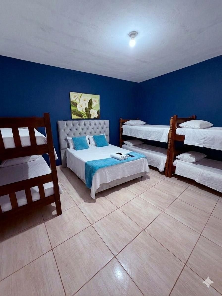Una habitación con una litera, una cama individual y una silla de madera.