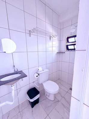 A bathroom with a sink, toilet, and mirror. - Pousada Villa Caiçara (Ubatuba)