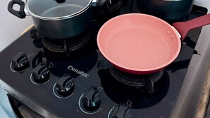 A kitchen stove with four pots and a pan, a red handle, and a power outlet. - Pousada Villa Caiçara (Ubatuba)