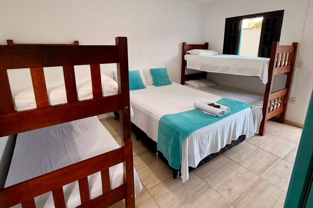 A room with bunk beds, a window with shutters, and a ceiling light.