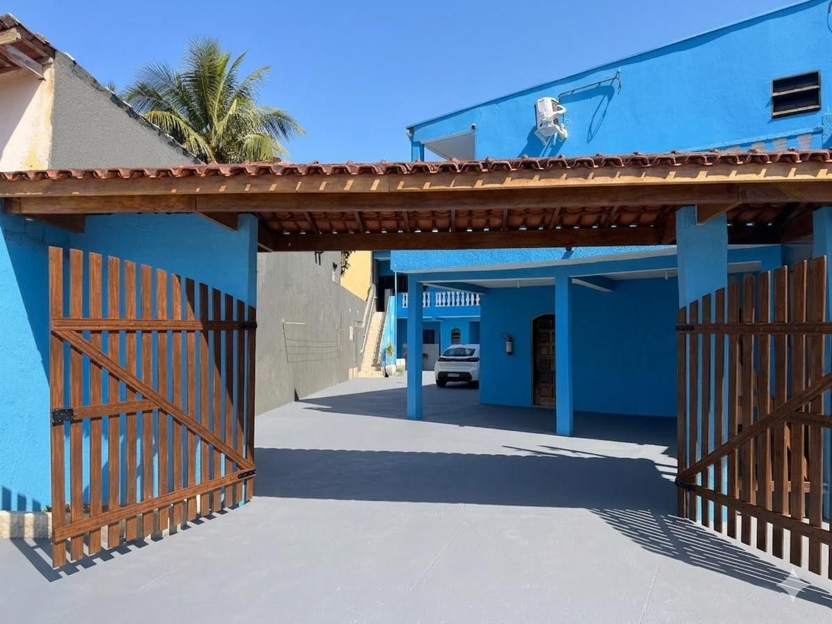 Uma entrada protegida por grades para um edifício com fachada azul e telhado em telhas.