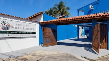 Una villa con fachada azul, entrada protegida por una reja y un cartel anunciando la propiedad.