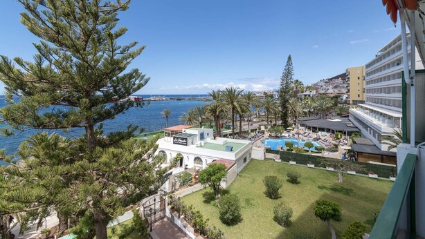 Ein Resort mit Pool, Palmen und Meerblick.