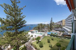 Un complexe hôtelier doté d’une piscine, de palmiers et offrant une vue sur la mer.