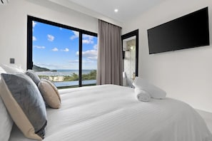 Ein modernes Hotelzimmer mit einem großen Bett, einem Flachbildfernseher und Blick aufs Meer.