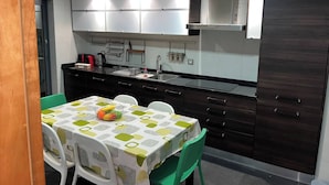 A compact kitchen with modern appliances, a dining table with chairs, and a dark wooden cabinet. - Luxury Apartment, Near Beach&golf (Seixal)