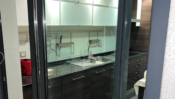 A modern kitchen with a glass partition, stainless steel appliances, and a built-in oven. - Luxury Apartment, Near Beach&golf (Seixal)