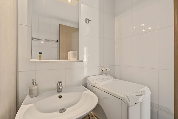 Et badeværelse med en hvid vask, et spejl og et toilet.