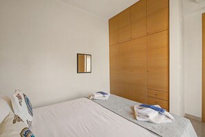 A bedroom with a bed, a wooden wardrobe, and a small mirror on the wall. - Apartment 'Happiness in Chania' with Wi-Fi (Chania)