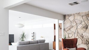 Ein modernes Wohnzimmer mit einem grauen Sofa, einem roten Sessel, einem runden Couchtisch und einer Steinwand.