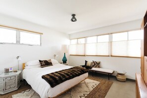 Ein Schlafzimmer mit Bett, Nachttischen, einer Lampe, einem Radio und einem Fenster.