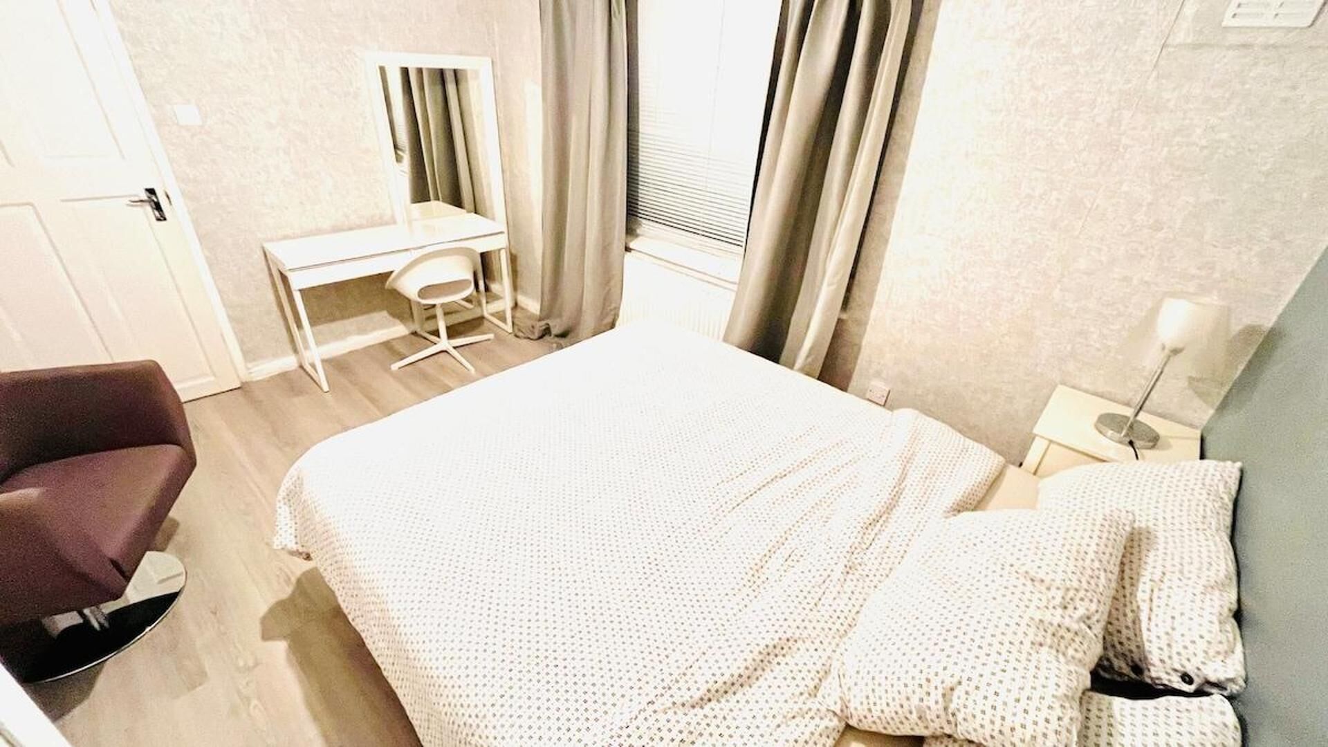 Une chambre à coucher comprenant un lit, un bureau, une chaise et une table de chevet.