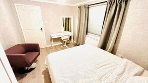 Ein Hotelzimmer mit Bett, Schreibtisch, Stuhl und Tür.
