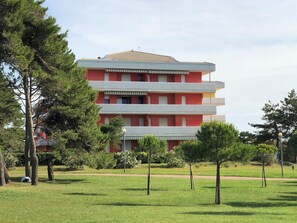 A multi-story building with a red facade, balconies, and a flat roof. - Peaceful Retreat in a Seafront Building (San Michele al Tagliamento)