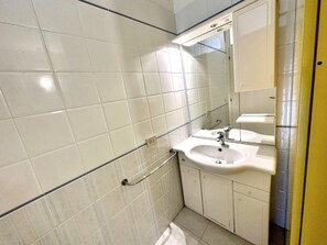 Et badeværelse med hvide fliser, en vask, et spejl og en håndklædestang.