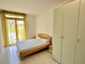 A bedroom with a bed, a wardrobe, and a window with curtains. - Peaceful Retreat in a Seafront Building (San Michele al Tagliamento)