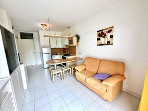 A compact living space with a kitchenette, a dining area, and a sofa. - Peaceful Retreat in a Seafront Building (San Michele al Tagliamento)