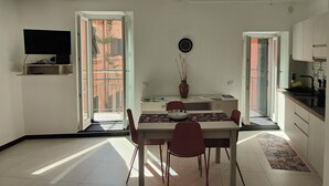 Un espacio habitable compacto con comedor, cocina y televisor montado en la pared.