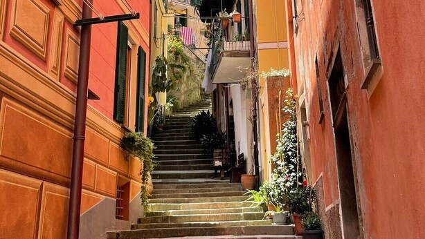 Una calle estrecha con escalones de piedra que conducen a la entrada de un edificio, rodeada de edificios coloridos.