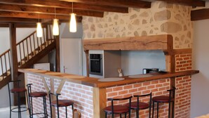 A kitchen with a brick wall, wooden counter, and bar stools.