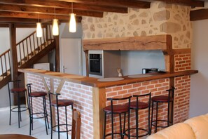 Een keuken met een bakstenen muur, een houten aanrecht en barstoelen.