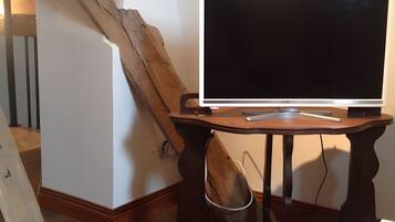 Een kamer met een houten bureau, een flatscreen televisie en een houten trap.