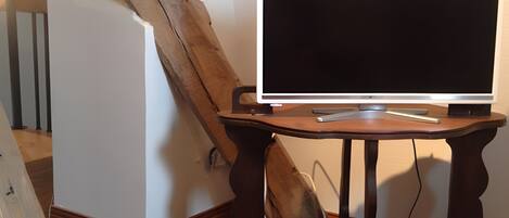 Una habitación con un escritorio de madera, un televisor de pantalla plana y una escalera de madera.