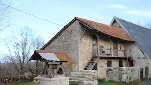 A stone building with a metal roof, a wooden staircase, and a small porch.