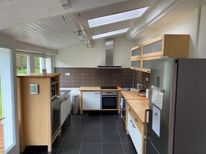 Eine moderne Küche mit Einbauofen, Kühlschrank und einem Fenster mit Blick auf Grünflächen.