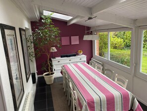 Ein Schlafzimmer mit Bett, Schreibtisch, Stuhl, Zimmerpflanze und Fenster.