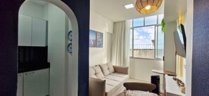 A modern living room with a sofa, a small table, and a TV. - CODDJ0100 - Cond. Nossa Sra de Lourdes (Salvador)