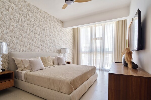 A bedroom with a large bed, a ceiling fan, a TV, and a window with curtains. - New! Private Villa with Pool Near White Sands Beach, Punta Cana (Punta Cana)