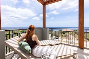 A balcony with a view of the sea, a person sitting on a lounge chair, and a railing. - Luxury penthouse with panoramic sea views (Sint Willibrordus)