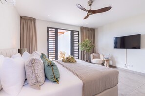 A modern hotel room with a bed, a ceiling fan, a television, and a view of the outside. - Luxury penthouse with panoramic sea views (Sint Willibrordus)