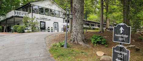 A two-story lodge with a balcony, a signpost with directions to Timberlodge 503 and 502, and a pathway leading to the building.
