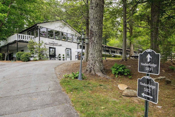 A two-story lodge with a balcony, a signpost with directions to Timberlodge 503 and 502, and a pathway leading to the building.